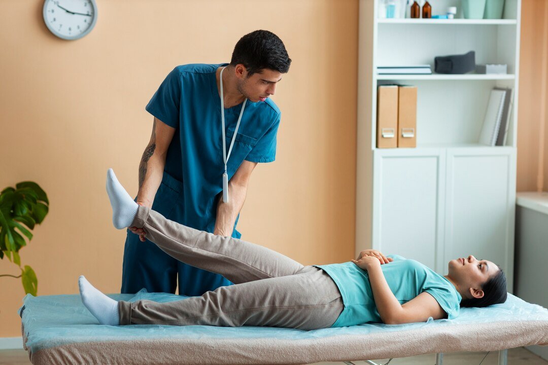 Physiotherapist assessing a patient's leg mobility on a treatment table